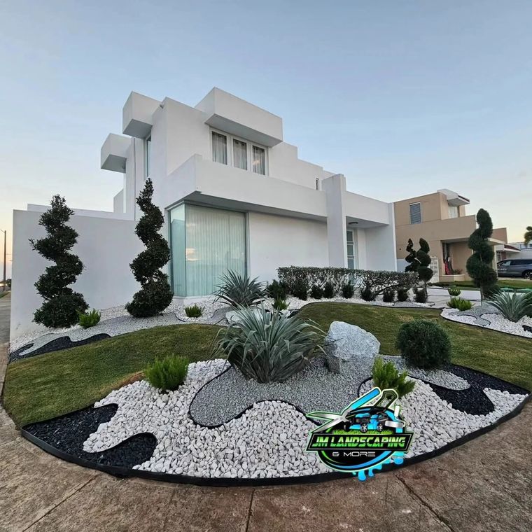 Isla frontal con piedra blanca y negra, roca decorativa y topiarios en espiral