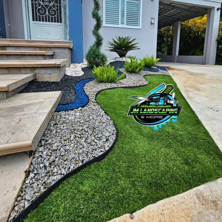 Entrada de casa con grama, piedra gris y cinta de piedra azul