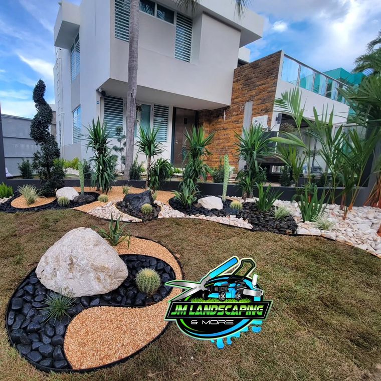 Frente de casa con roca grande, piedra negra, mulch color crema y plantas
